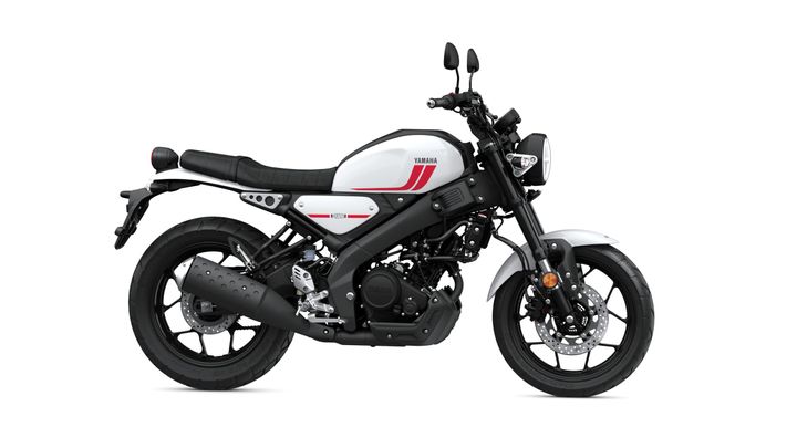 A sleek white and black Yamaha motorcycle is shown from the side, featuring a minimalist design with red accents, a low seat, and stylish wheels.