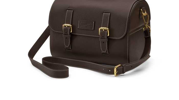 Brown leather messenger bag with a flap, featuring two buckled straps, a handle on top, and a detachable shoulder strap.