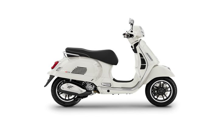 A white Vespa scooter with a black seat, shown from the side, featuring a sleek design and modern components.
