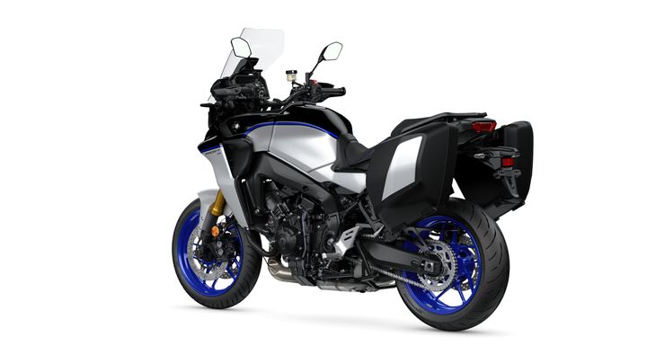 A silver and black adventure motorcycle with blue wheels and panniers, angled to show the left side and rear.