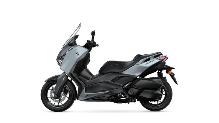 A sleek gray and black Yamaha XMAX scooter is shown from the side, featuring modern design elements, a large windshield, and stylish dual-tone bodywork.