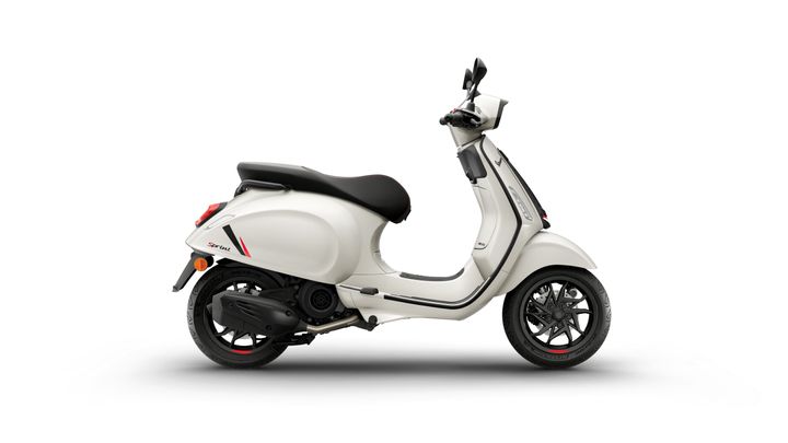 A white scooter parked sideways with a black seat and stylish wheel design, featuring red accents on the body.