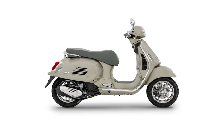 A beige scooter with a grey seat, positioned at a slight angle, featuring chrome accents and five-spoke wheels.