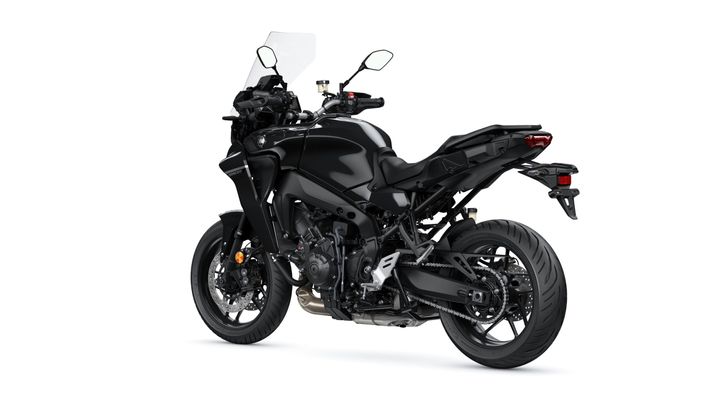 A sleek black motorcycle viewed from the rear, showcasing its modern design, features such as a windscreen, dual exhaust, and sporty tires.