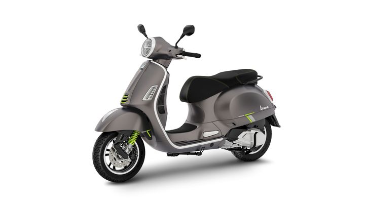A sleek gray scooter with black accents and green highlights, featuring a rounded front, single headlight, and a comfortable seat, positioned against a white background.