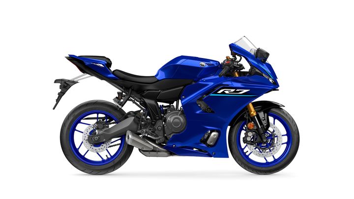 A sleek blue Yamaha R7 motorcycle viewed from the side, showcasing its aerodynamic design, sporty frame, and distinct blue accents on the wheels.