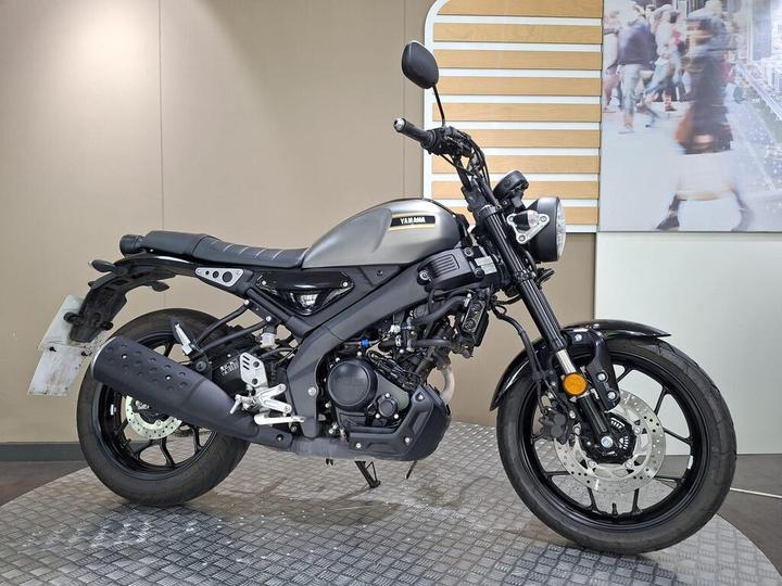 Yamaha XSR 125 2026 A gray Yamaha motorcycle is positioned on a textured floor, showcasing its sleek design and black wheels. The bike features a modern aesthetic with a round headlight and minimalist bodywork, set against a neutral background that suggests an indoor showroom environment.