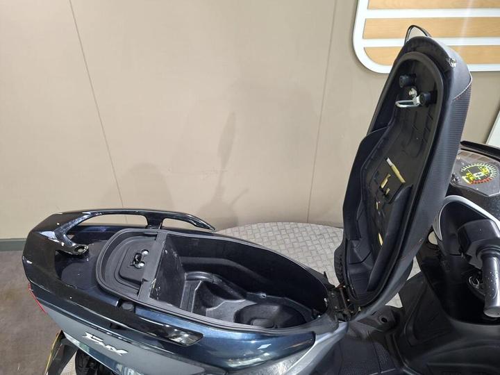 A close-up view of a scooter's storage compartment with the seat raised, showcasing the interior space and securing mechanism.