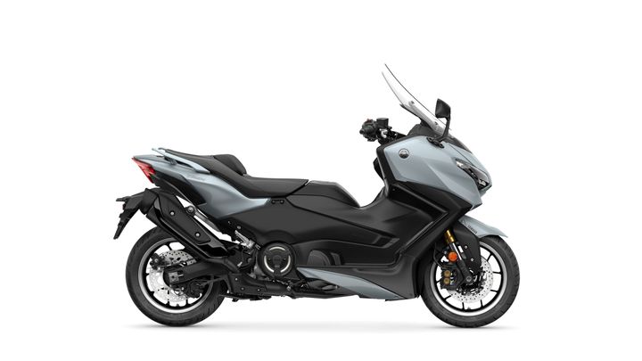 A sleek gray scooter with a modern design, featuring a low-slung body, large front windshield, and stylish side panels. The motorcycle is positioned against a white background, showcasing its distinctive curves and details.