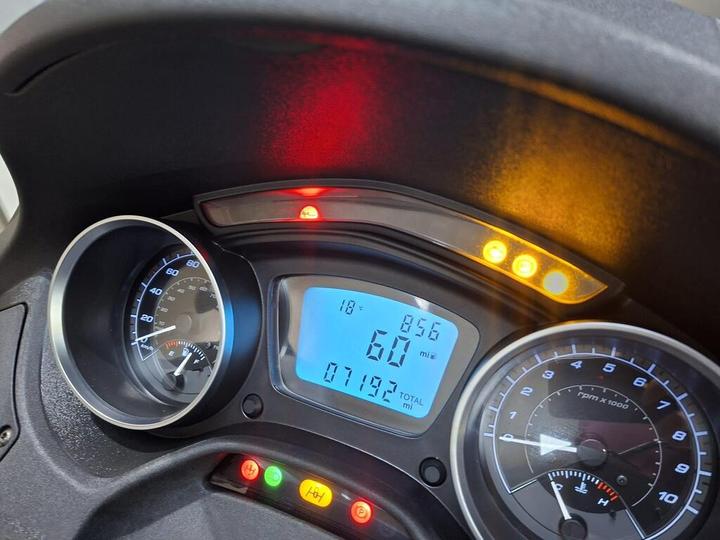 Dashboard of a vehicle displaying speed, odometer, and warning lights, including indicators for oil pressure and temperature.