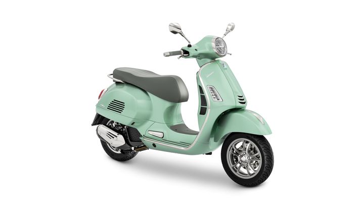 A mint green Vespa scooter with a grey seat, showing a sleek design and chrome details, positioned on a white background.