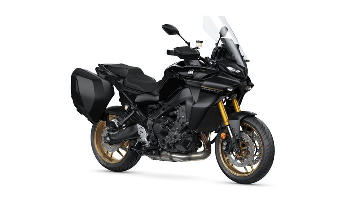 A sleek black motorcycle with gold accents and panniers, positioned at an angle to showcase its design features, including a tall windshield and sporty seating.