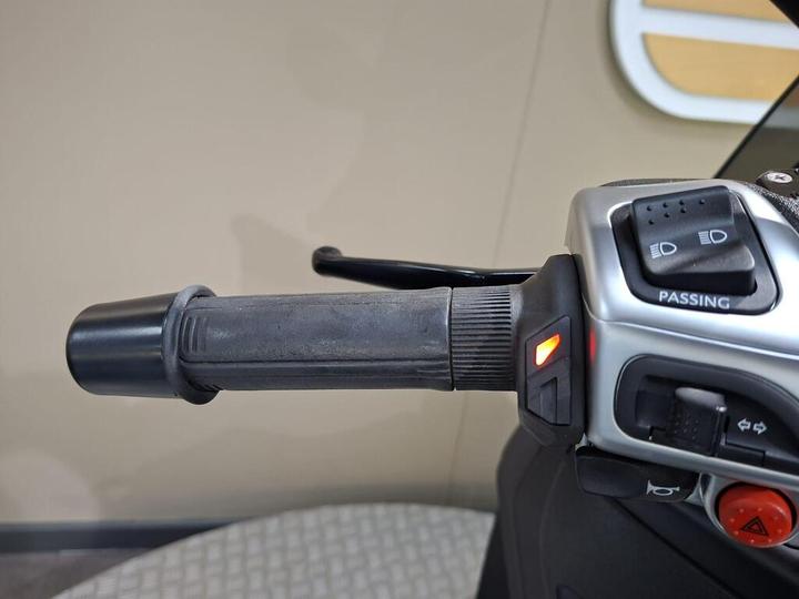 Close-up view of a motorcycle handlebar grip with controls, including a passing light switch and an illuminated indicator light.