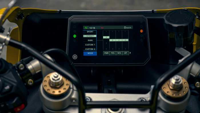 Close-up view of a motorcycle's digital display showing options for riding modes, including Sport, Street, Rain, and Custom settings, along with speed, time, and various system indicators.