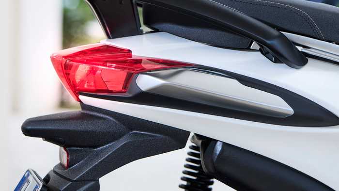 Close-up of the rear section of a motorcycle featuring a sleek black spoiler, a red tail light, and a minimalist design with a gray seat and part of the rear suspension visible.