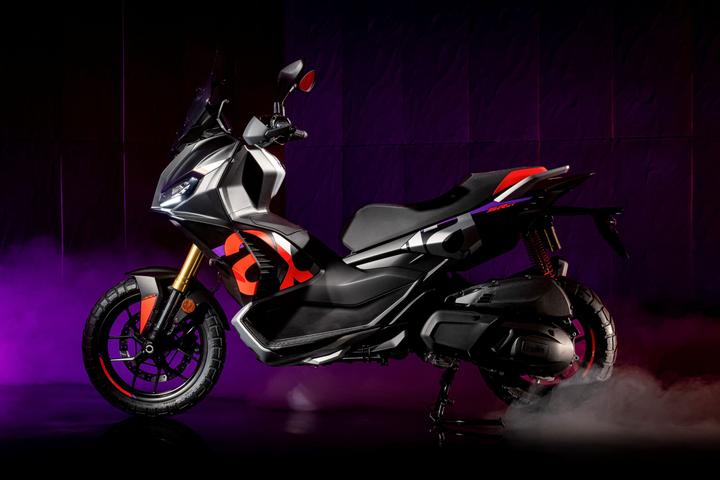 A sleek, modern motorcycle with a black and red design, showcasing a prominent front headlight and a sporty silhouette against a moody purple background with smoke effects.