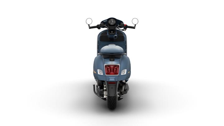 A blue scooter viewed from the rear, showcasing its sleek design, round mirrors, and distinctive taillight. The background is plain white, emphasizing the scooter's features.