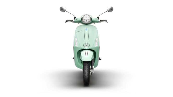 A front view of a mint green scooter with a vintage design, showcasing its round headlight, mirrors, and a sleek body.