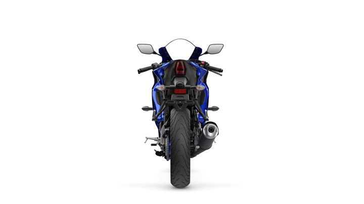 Rear view of a blue sports motorcycle, showcasing its slim profile, dual exhaust, and distinctive taillight design against a white background.