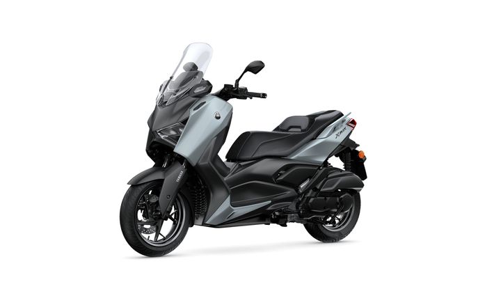 A sleek, modern scooter in a combination of black and light silver colors, featuring a large windshield, comfortable seat, and sporty design.
