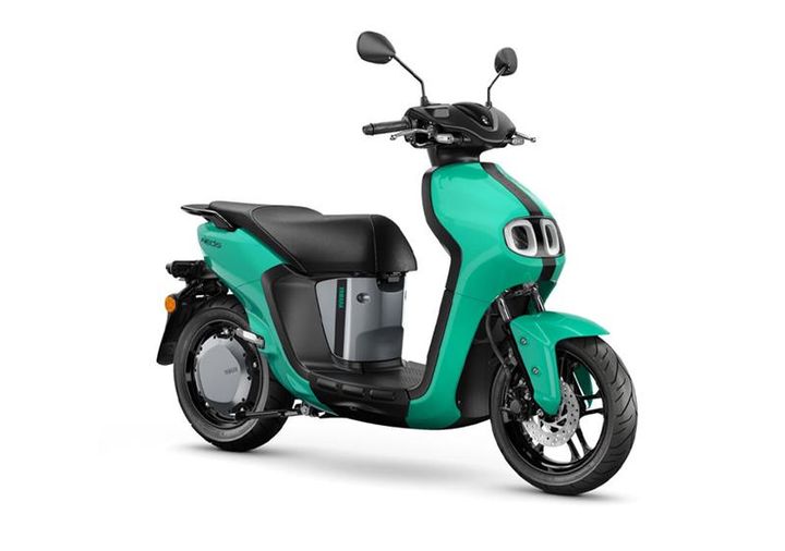 A turquoise electric scooter with a modern design, featuring a black seat and dual headlights, positioned at an angle to showcase its sleek body and front wheel.