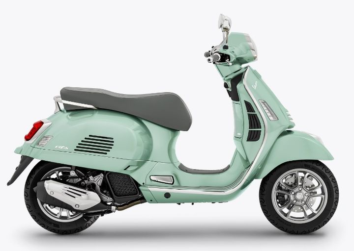 A mint green Vespa scooter positioned at a three-quarter angle on a white background.