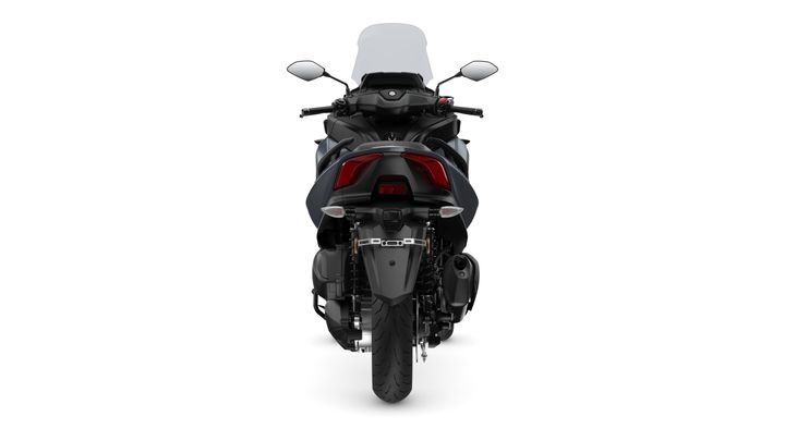 A rear view of a motorcycle showcasing its sleek design, clear tail lights, and a dual exhaust on the right side. The background is white, emphasizing the motorcycle's features.