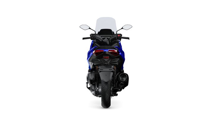 A rear view of a blue motorcycle with a tall windshield, dual rear lights, a single exhaust, and black accents on the body and tires set against a white background.