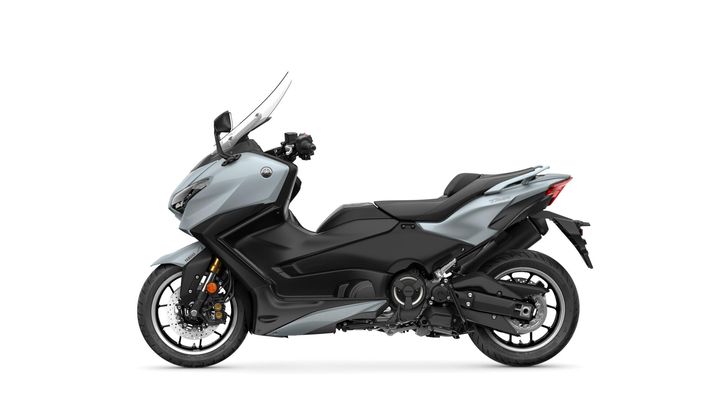 A sleek gray and black Yamaha TMAX scooter is shown in profile, featuring a modern design with a windshield, sporty wheels, and dual front disc brakes.