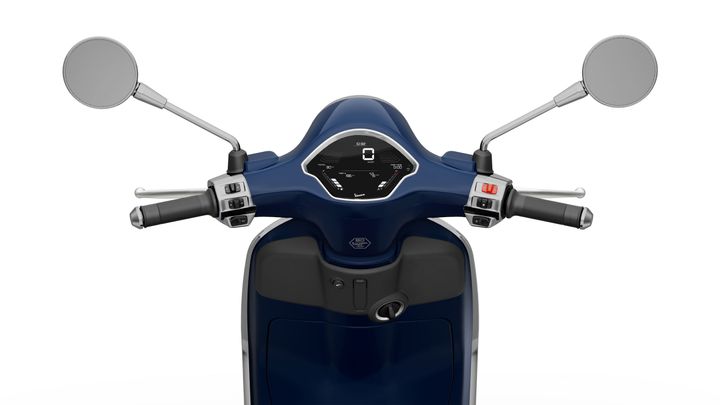 Close-up view of a scooter's handlebar with a dark blue finish, featuring mirrors, grips, and a central dashboard displaying a digital speedometer.