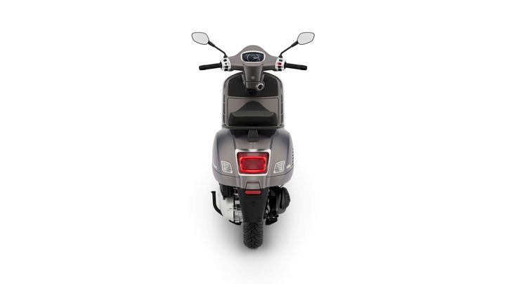 A gray scooter viewed from the rear, showcasing its tail light, tires, and side-mounted exhaust.