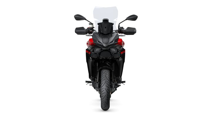 A modern motorcycle with a sleek black and red design, featuring a tall windshield, dual headlights, and a robust front tire, viewed head-on against a white background.