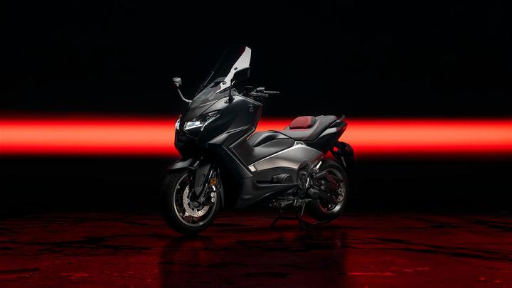 A sleek black motorcycle is displayed against a dark background, with a striking red light strip behind it. The motorcycle features a modern design, large windscreen, and sporty contours, highlighting its premium look.