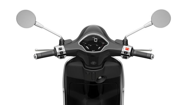 Close-up view of a scooter's handlebars showing the grips, mirrors, and digital display with speed and fuel indicators.