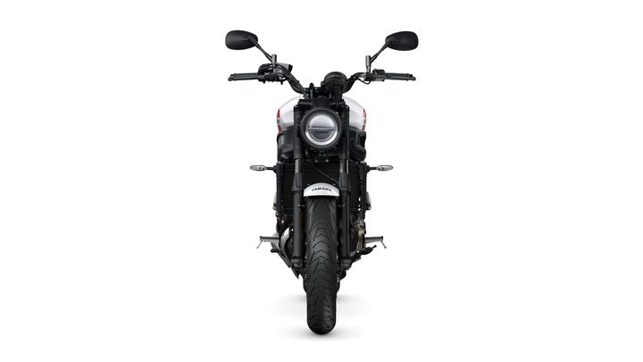 A front view of a black motorcycle with a round headlight, handlebars, and a wide tire, set against a white background.