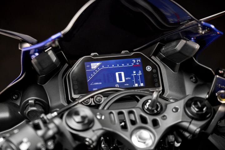 Close-up of a motorcycle dashboard displaying a digital speedometer, gear indicator, and odometer reading, set against a dark background.