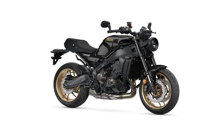 A sleek black Yamaha XSR900 motorcycle with a sporty design, featuring gold alloy wheels and a streamlined body, positioned on a white background.