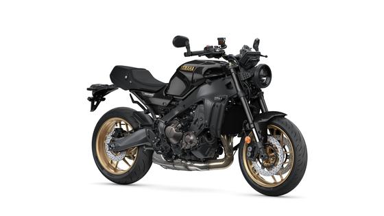 A sleek black Yamaha XSR900 motorcycle with a sporty design, featuring gold alloy wheels and a streamlined body, positioned on a white background.