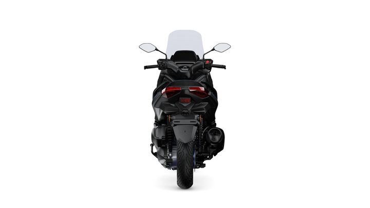 A rear view of a sleek black motorcycle with a tall windshield, featuring modern tail lights and a distinct exhaust system.
