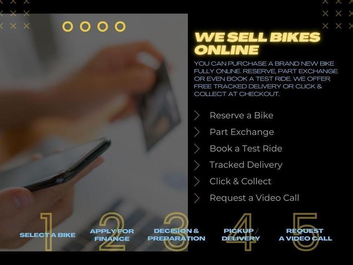 A smartphone held in one hand displays a credit card, with a blurred background of a laptop. Text on the right outlines online bike purchasing options, including selecting a bike, financing, test rides, tracked delivery, click & collect, and video calls.