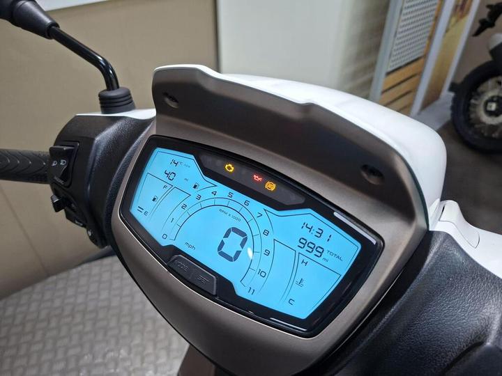 Digital display of a scooter's dashboard, showing speedometer, odometer reading of 999 miles, temperature of 14°C, and various warning lights.
