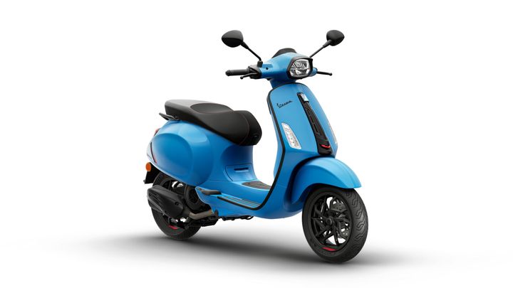 A bright blue scooter with a black seat, featuring a modern design and sleek curves, positioned at a slight angle against a white background.