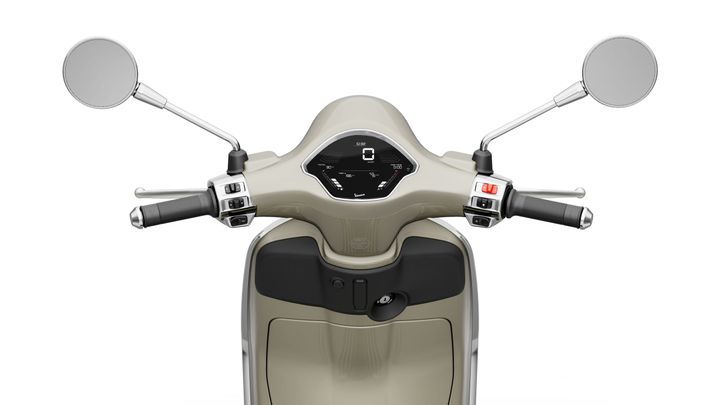 Close-up view of a scooter's handlebars, featuring chrome mirrors, a digital speedometer, and control buttons on each side, all set against a neutral background.