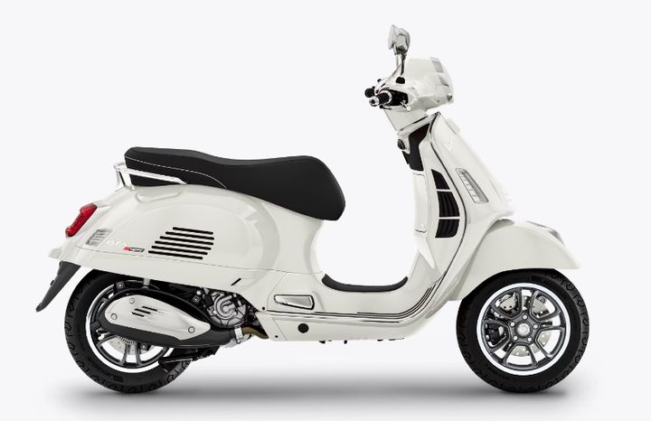 A white modern Vespa scooter with black seats positioned in profile view against a white background.