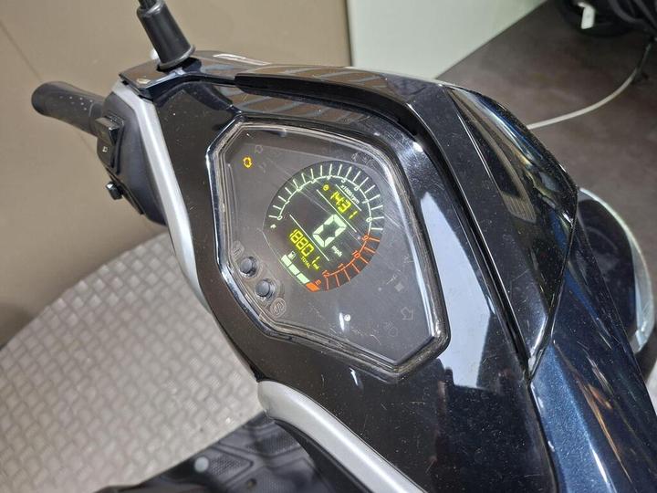 Close-up view of a scooter's digital dashboard displaying speed at 43 km/h, battery level, and other indicators on a dark surface.