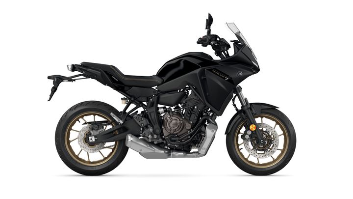 A side view of a black Yamaha Tracer 7 motorcycle, featuring a sleek design, gold-accented wheels, and a windshield.