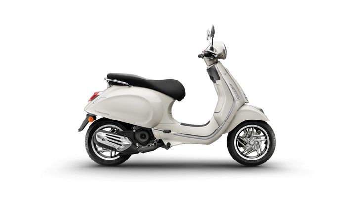 A sleek, light-colored scooter is shown in profile, featuring a rounded body, black seat, and shiny silver wheels, set against a plain white background.