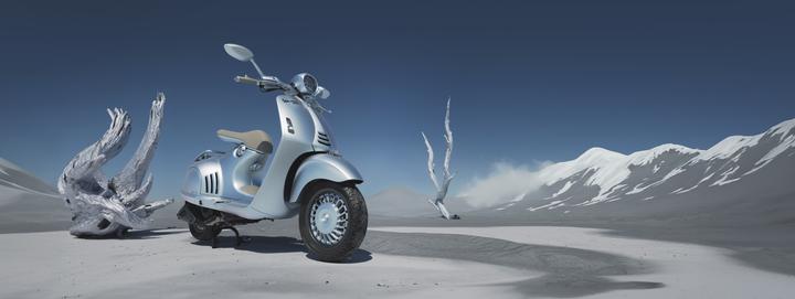 A sleek silver scooter parked on a desolate, sandy landscape with white mountains in the background and abstract white sculptures nearby, under a clear blue sky.