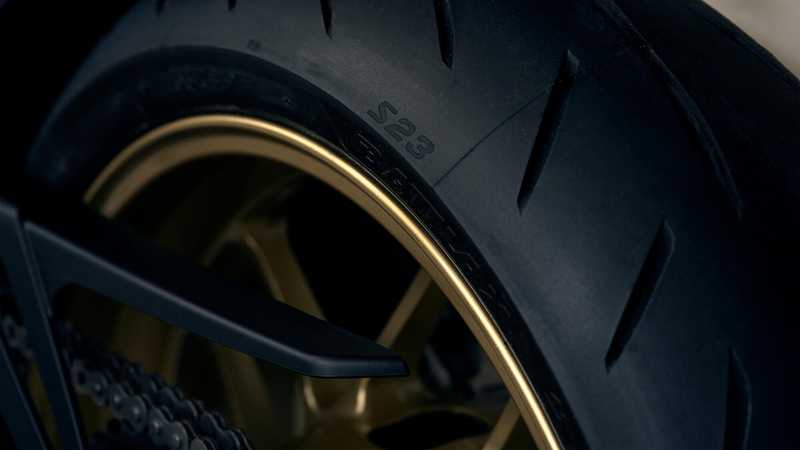 Close-up of a motorcycle tire with a textured black surface and a gold rim, featuring the label "S23" on the sidewall.
