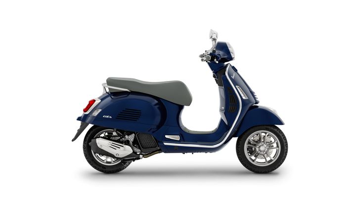 A side view of a navy blue scooter with a grey seat and chrome accents, featuring a rounded design and a stylish rear light.